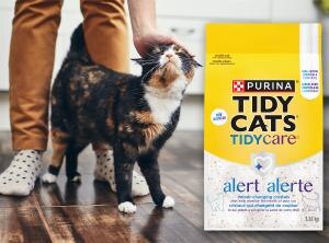 cat going around owner's leg standing next to a tidy cat product bag